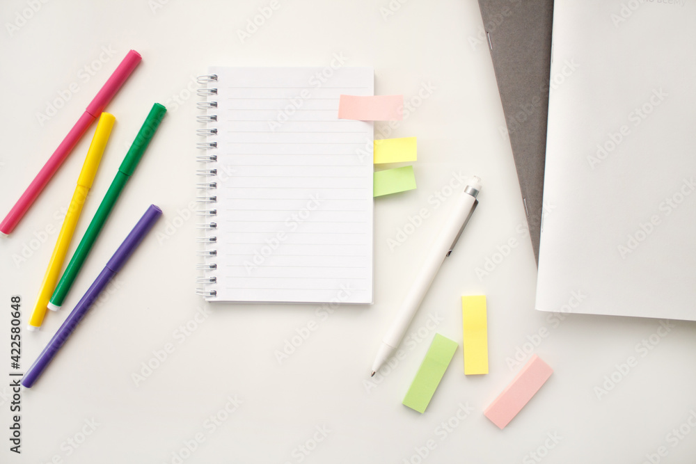 An open notebook on a white background with colored pencils and felt-tip pens, a ruler and scissors. The notebook lies on a plain background with space for writing. Composition of writing to-dos for t An open notebook on a white background with colored pencils and felt-tip pens, a ruler and scissors. The notebook lies on a plain background with space for writing. Composition of writing to-dos for t