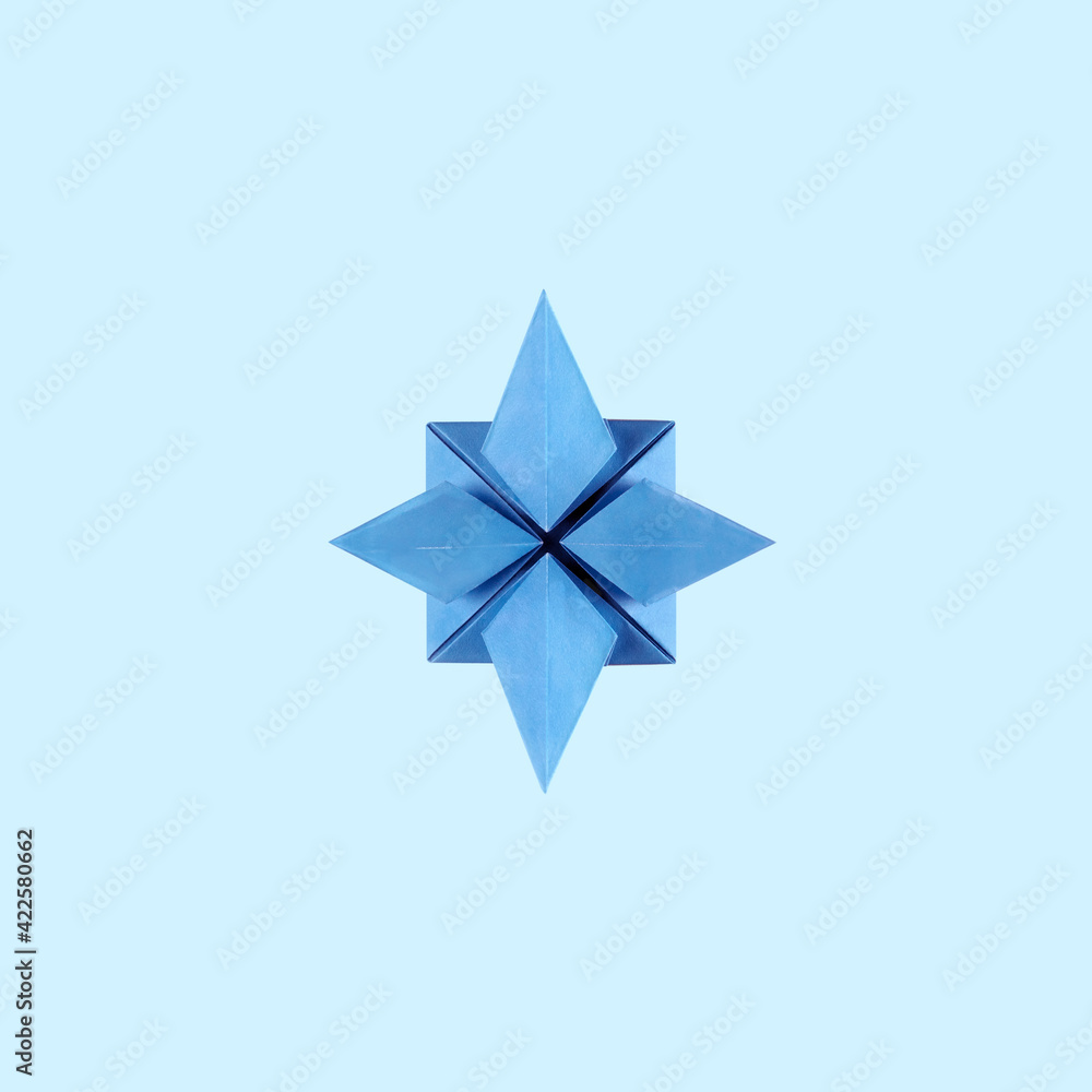 Origami blue paper rose of the winds on blue background Origami blue paper rose of the winds on blue background