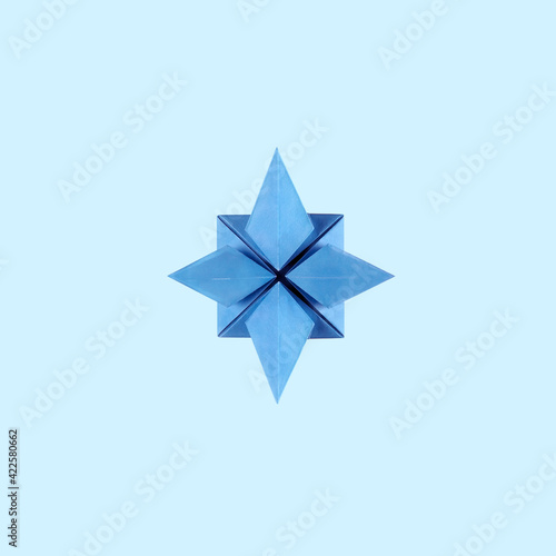 Origami blue paper rose of the winds on blue background