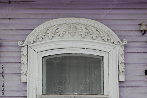 Ornamental carved window, frame on lilac traditional national old wooden rural house in Gorodets city, Russia. Russian folk style in architecture. Gorodets architectural monument, Gorodets landmark photo