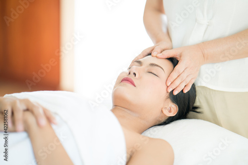 A young Asian woman getting a head massage It's in a spa shop. Young Asian girl relaxing with hand spa massage at beauty spa salon.