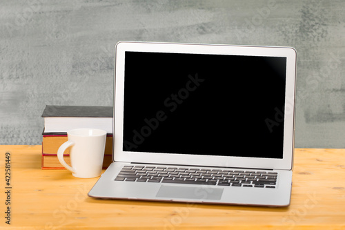 Laptop with blank screen, cup of coffee and books or notebooks on a wooden table. mockup for your text.home education concept