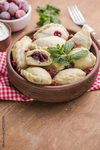 Pierogi with cherries. c. Traditional Ukrainian food. Cooked and served with sour cream and berry