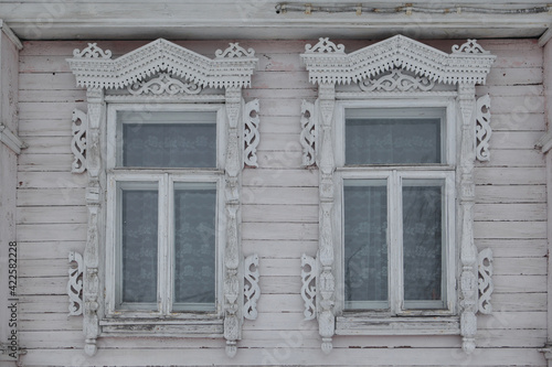 Ornamental carved windows, frames on pink traditional national old wooden rural house in Gorodets city, Russia. Russian folk style in architecture. Gorodets architectural monument, Gorodets landmark photo