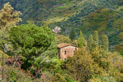 an abandoned house in the mountains of Eastern Sicily with spring vegetation and other distant houses among the reliefs photo