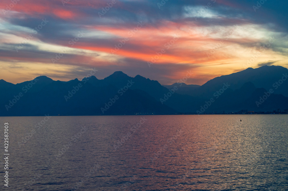 Bright colorful sky at sunset over the sea and mountains.