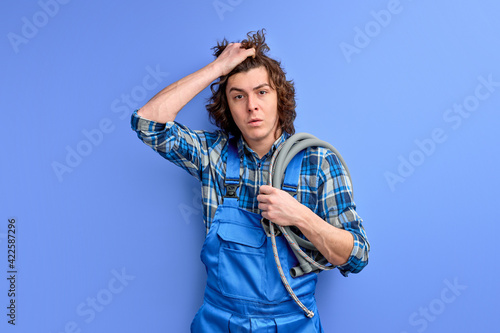 depressed plumber with hose looking at camera holding hand on head, upset