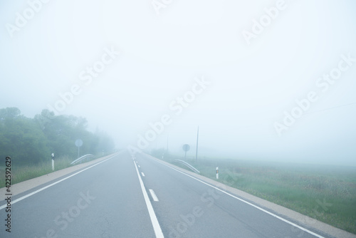 Mysterious road with nobody at spring foggy weather