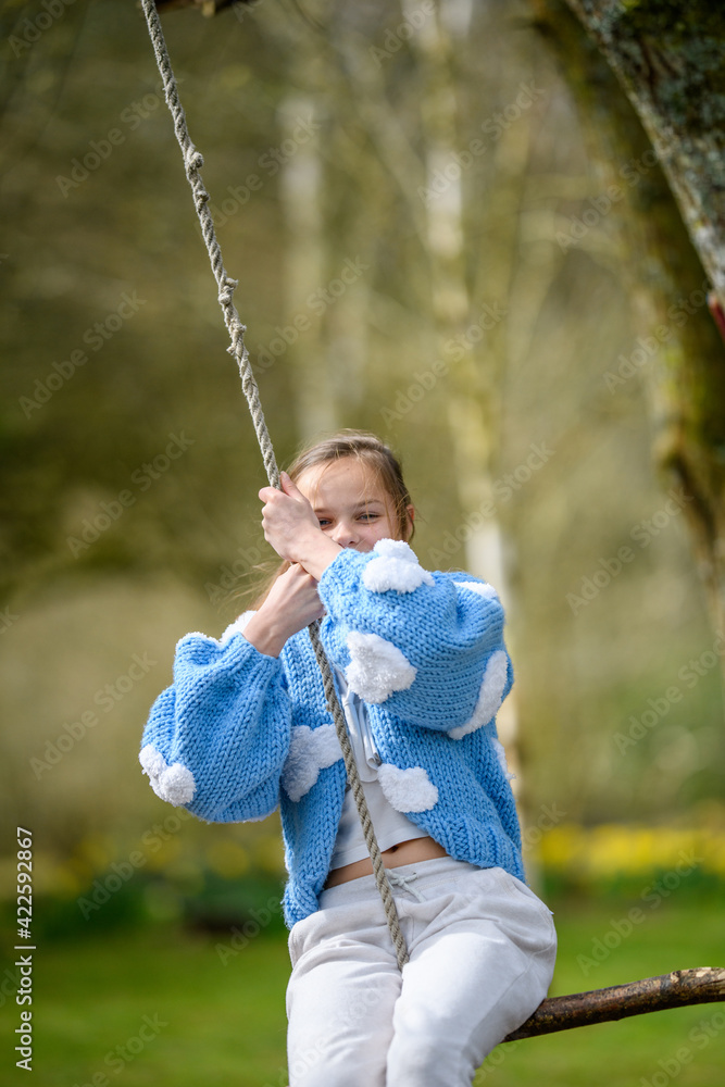 Girl on a stick swing.A young girl smiling while swinging on a stick swing at a park.