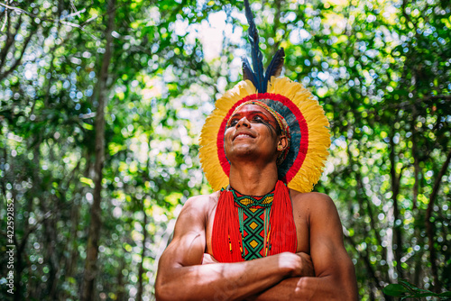 Indian from the Pataxó tribe, with feather headdress. Young Brazilian Indian looking to the left, smiling and arms crossed