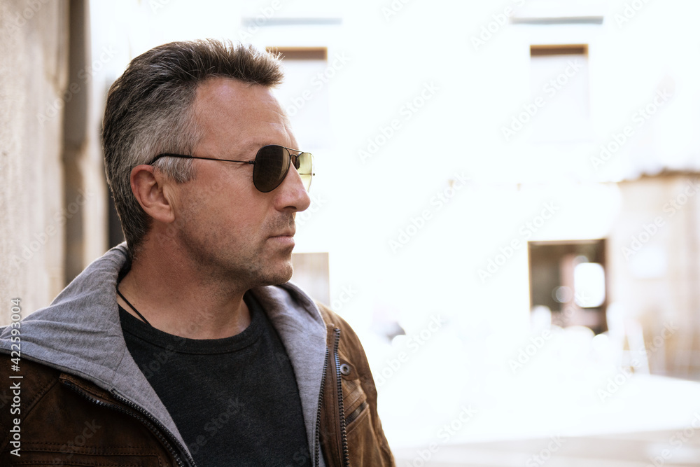 Fototapeta premium Urban outdoor portrait of a handsome mature man with sunglasses, street style at spring