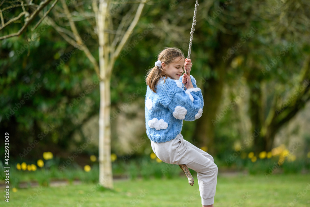 Girl on a stick swing.A young girl smiling while swinging on a stick swing at a park.