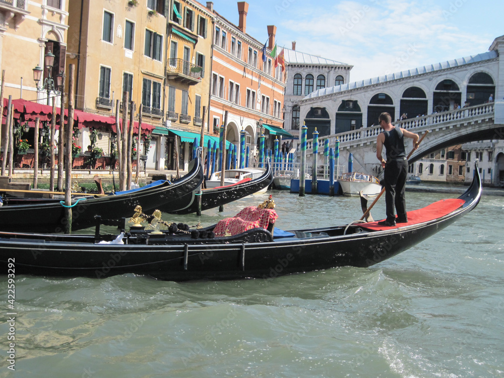 Venice old city grand canal with gondolas and boats. Romantic swimming in the morning. Comfotrable transportation to ancient historic hotel. Scenic Venetian scape on a sunny day.