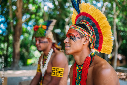 two Indians from the Pataxó tribe. Brazilian Indian from southern Bahia with feather headdress, necklace and traditional facial paintings looking to the left