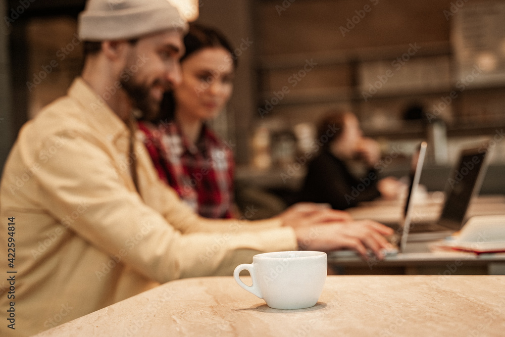 cup of coffee on table near freelancers in face cup of coffee on table near freelancers in face