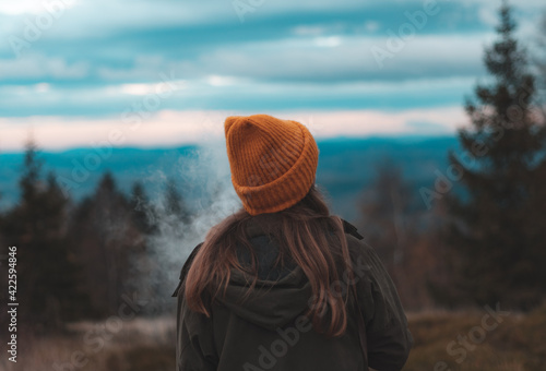 Fototapeta Naklejka Na Ścianę i Meble -  Blonde woman in a cap relaxes at sunset in the Beskid Mountains.