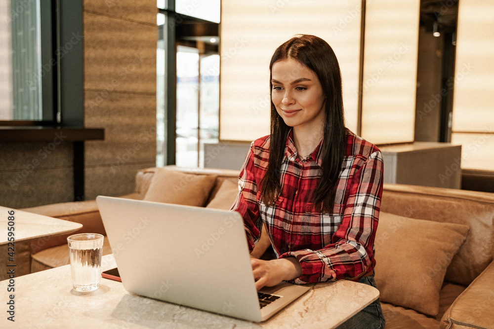 brunette freelancer using laptop while working remotely in cafe brunette freelancer using laptop while working remotely in cafe