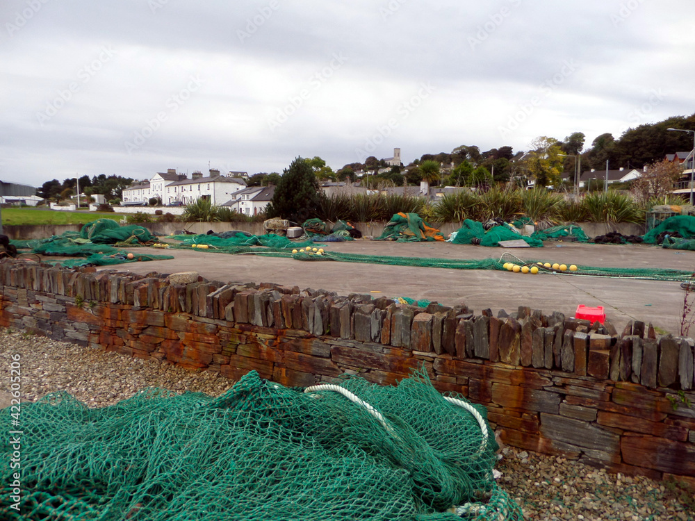 Grüne Fischernetze liegen an einem Hafen an der Küste Irlands. Hafen Landschaft an der englischen britischen Küste. Hafenszene mit grünen Netzen und Steinstrand .