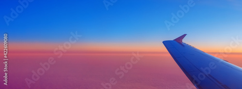 view of the plane's wing and pink clouds at sunset
