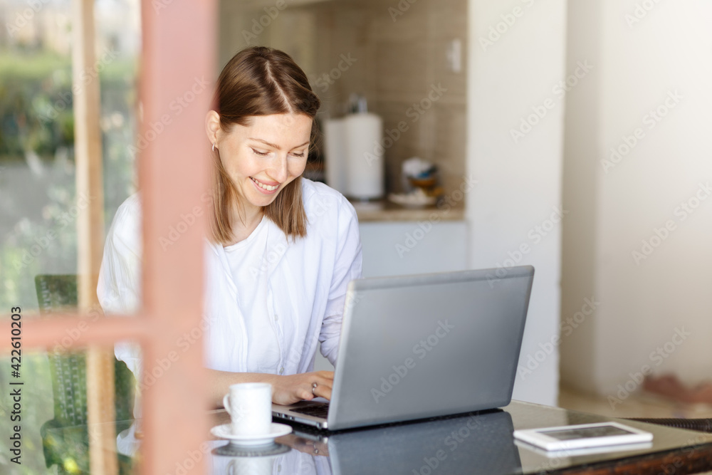 Attractive young woman working on a desktop computer smiling as she leans forwards reading text on the screen, view over the monitor and print text Attractive young woman working on a desktop computer smiling as she leans forwards reading text on the screen, view over the monitor and print text