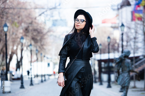 Beautiful russian girl dressed in black leather clothes and eyeglasses. Rock style european woman in urban background. © romeof
