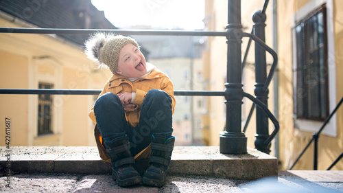 Foto Portrait of down syndrome child outdoors in town, making faces.
