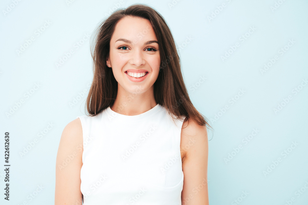Closeup portrait of young beautiful smiling female in trendy summer white t-shirt. Sexy carefree woman posing near light blue wall in studio. Positive model having fun indoors. Cheerful and happy Closeup portrait of young beautiful smiling female in trendy summer white t-shirt. Sexy carefree woman posing near light blue wall in studio. Positive model having fun indoors. Cheerful and happy