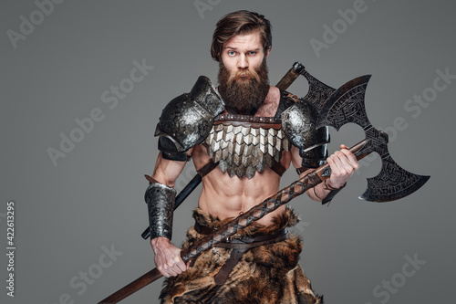 Фотография Handsome antique viking warrior with an axe in gray background