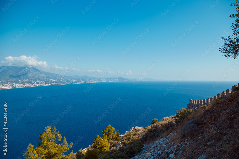 Sunny sea panorama landscape of Alanya Castle in Antalya district, Turkey. Popular tourist destination with high mountains. Summer sunny day and beautiful sea background