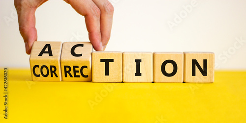 Action or correction symbol. Businessman turns wooden cubes and changes the word correction to action. Beautiful yellow table, white background, copy space. Business and action or correction concept. photo