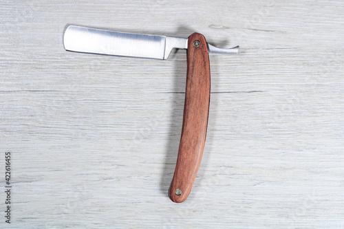 Classic straight razor on a bleached wood background.