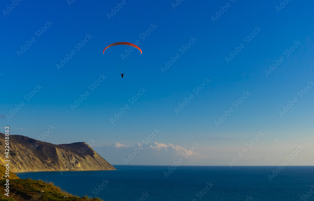 Paragliding in the sky. Paraglider tandem flying over the sea with mountains at sunset Paragliding in the sky. Paraglider tandem flying over the sea with mountains at sunset