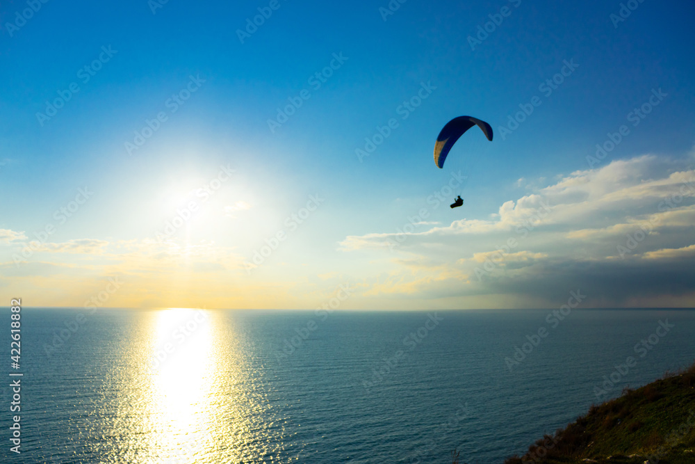 Paragliding in the sky. Paraglider tandem flying over the sea with mountains at sunset