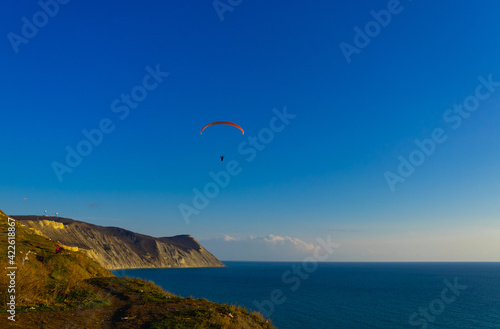 Paragliding in the sky. Paraglider tandem flying over the sea with mountains at sunset