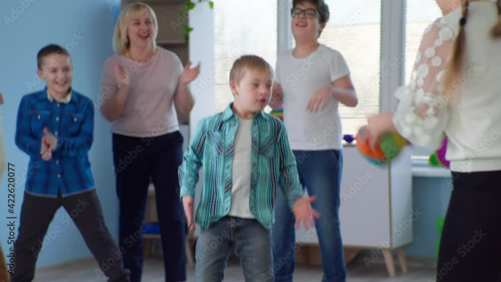 boy with down syndrome has fun throwing ball in developmental