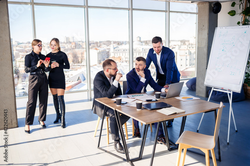 Business people working together in a modern office with cityscape view. The director tells the staff about new technologies. Office work concept