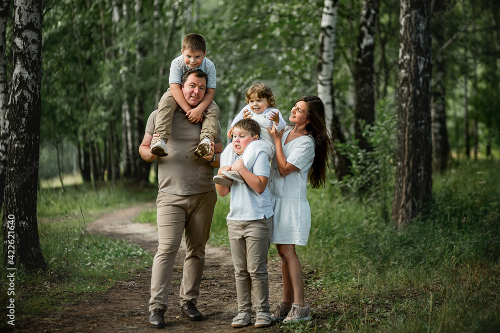 Obraz premium A happy family portrait with parents and their three sons in the park. Image with selective focus and toning