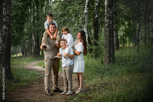 A happy family portrait with parents and their three sons in the park. Image with selective focus and toning