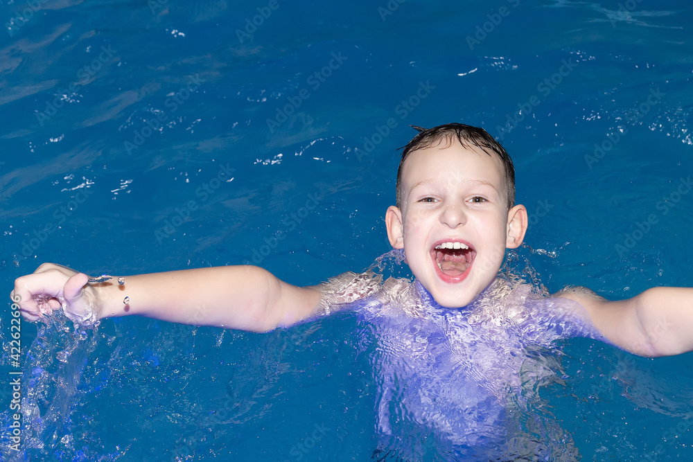 A Beautiful happy boy swims in the pool A Beautiful happy boy swims in the pool