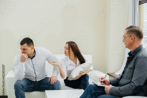 A young married couple of men and women talk to a psychologist at a therapy session. Psychology.