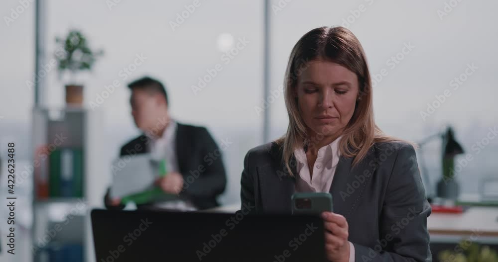 Beautiful busy young adult blonde businesswoman using mobile phone social network technology at shared workspace corporate coworking space. Beautiful busy young adult blonde businesswoman using mobile phone social network technology at shared workspace corporate coworking space.