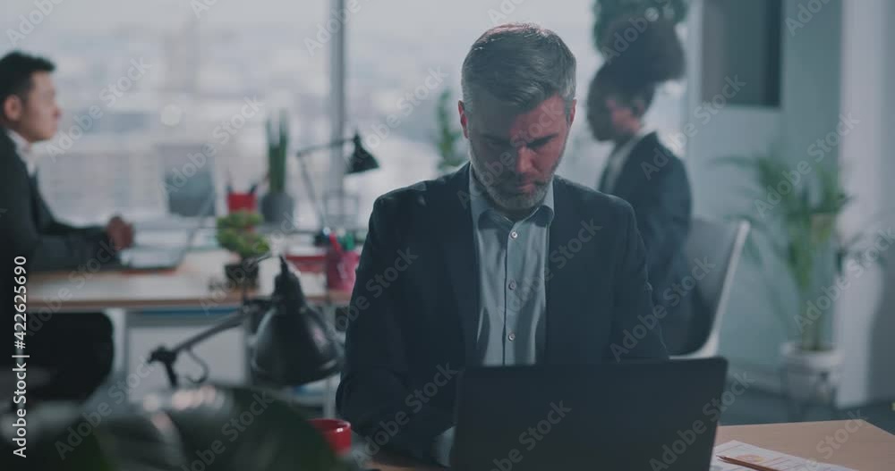 Startup businessman mature caucasian adult in formal business suit doing digital project finance report online using laptop in corporate office. Startup businessman mature caucasian adult in formal business suit doing digital project finance report online using laptop in corporate office.