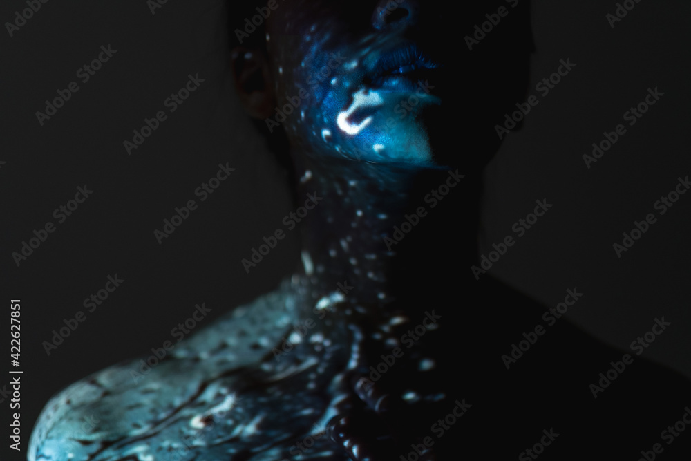 Art portrait. Soul healing. Chakra energy. Spiritual enlightenment. Cropped blue color woman silhouette with abstract water drops pattern on neck bare shoulders skin isolated on dark night background. Art portrait. Soul healing. Chakra energy. Spiritual enlightenment. Cropped blue color woman silhouette with abstract water drops pattern on neck bare shoulders skin isolated on dark night background.
