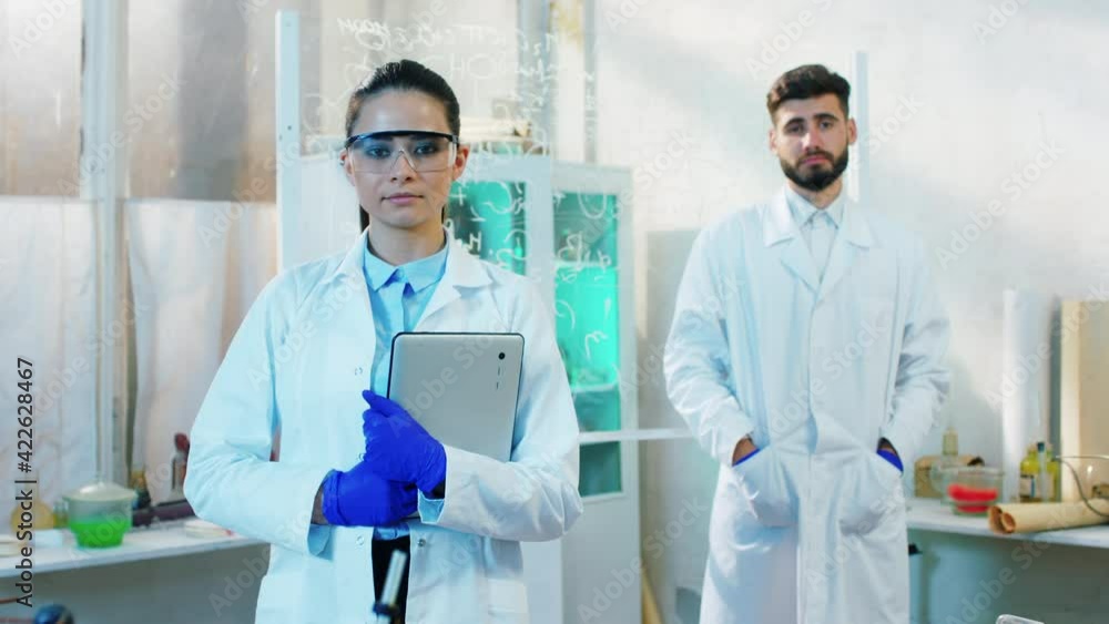Portrait of serious woman and man pharmacist in the biotechnology laboratory they posing in front of the camera and smiling cute Portrait of serious woman and man pharmacist in the biotechnology laboratory they posing in front of the camera and smiling cute