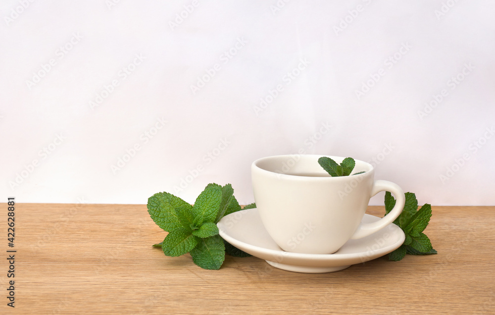 Leaves mint ( Mentha ) and cup mint tea on a light background Leaves mint ( Mentha ) and cup mint tea on a light background