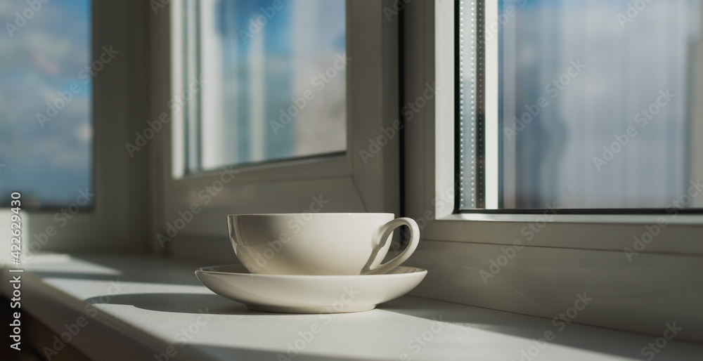 Cup and saucer on the windowsill made of plastic Cup and saucer on the windowsill made of plastic