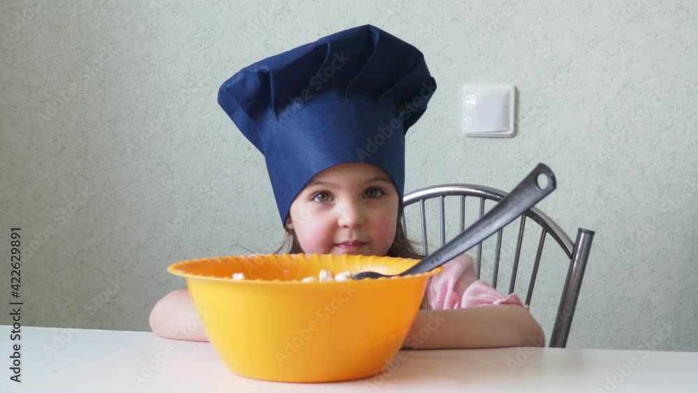 a cute little girl in a blue chef's caps, an apron prepares ginger dough cookies with her mother, figurines for Easter, Christmas, Thanksgiving. daughter cooking on kitchen. fun together make cookies a cute little girl in a blue chef's caps, an apron prepares ginger dough cookies with her mother, figurines for Easter, Christmas, Thanksgiving. daughter cooking on kitchen. fun together make cookies