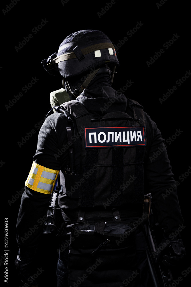Male in black uniform conforms to Police SWAT. Patch on the back with the inscription Police in Russian. Black background (red and blue lights)