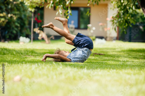 Active little girl makes a somersault on the backyard
