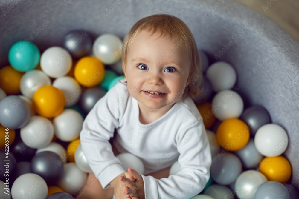 girl child sits in a pool with colorful plastic balls girl child sits in a pool with colorful plastic balls
